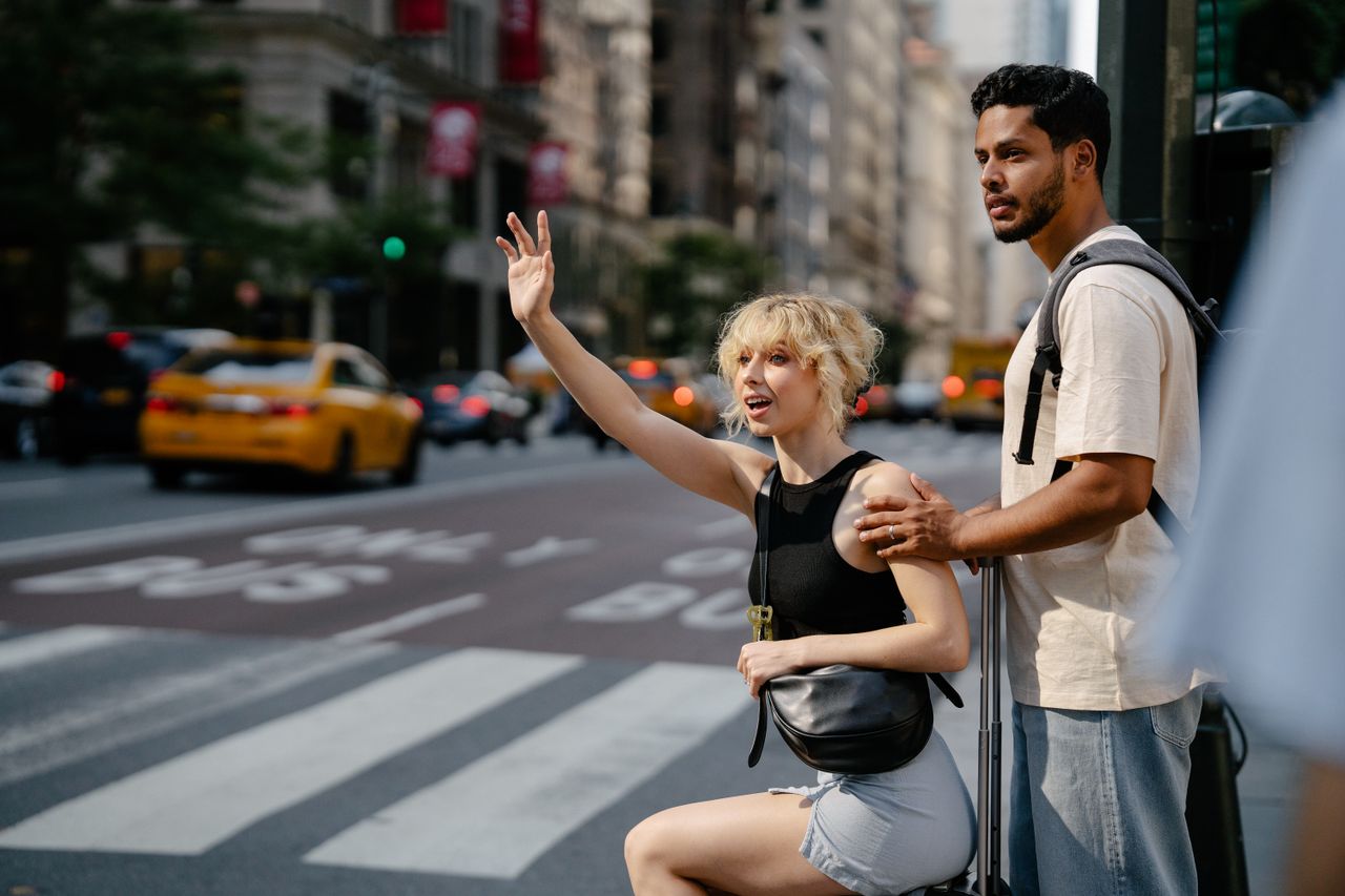 services-04 A young couple hailing a yellow cab on a bustling city street, exuding urban life.