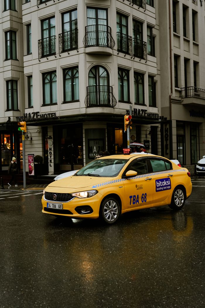 services-02 Yellow taxi in a rainy city intersection near a hotel, urban transport concept.